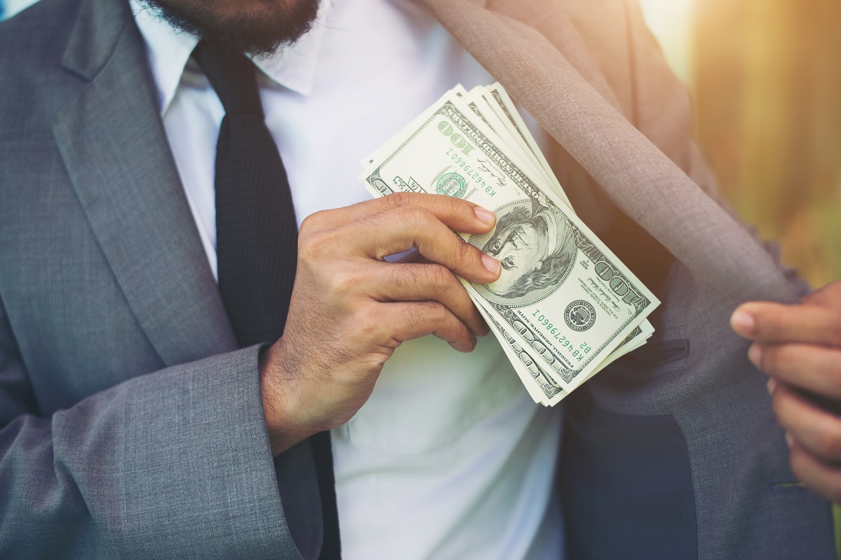 Businessman placing money into his pocket.