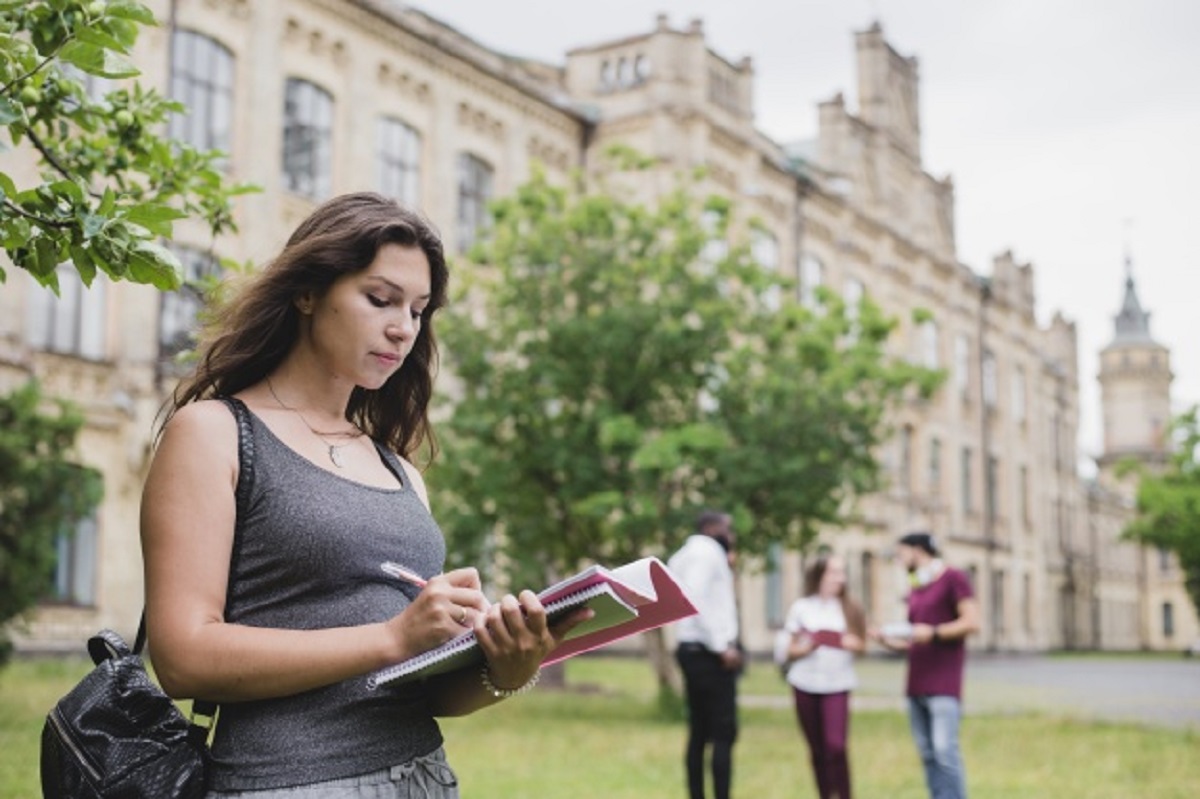 girl-holding-notebook-writing-standing-outside_23-2147657188