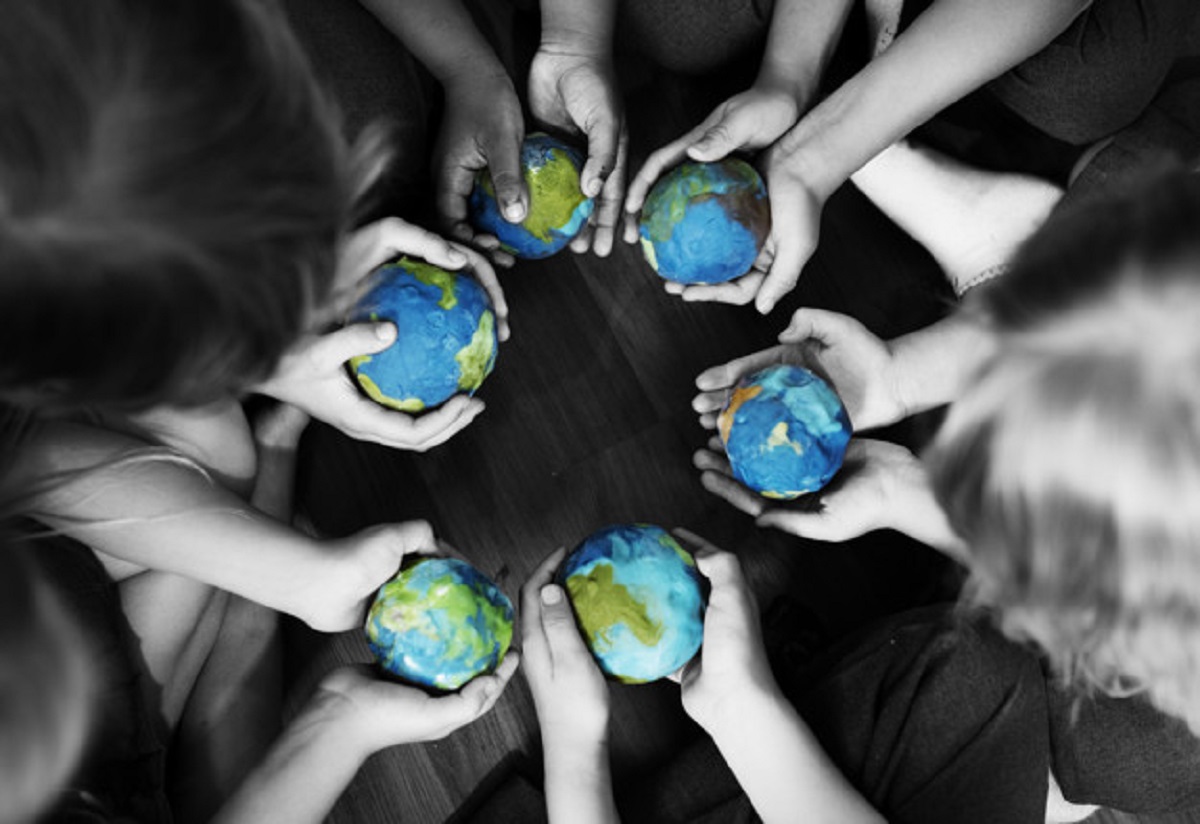 Group of diverse kids hands holding cupping globe balls together