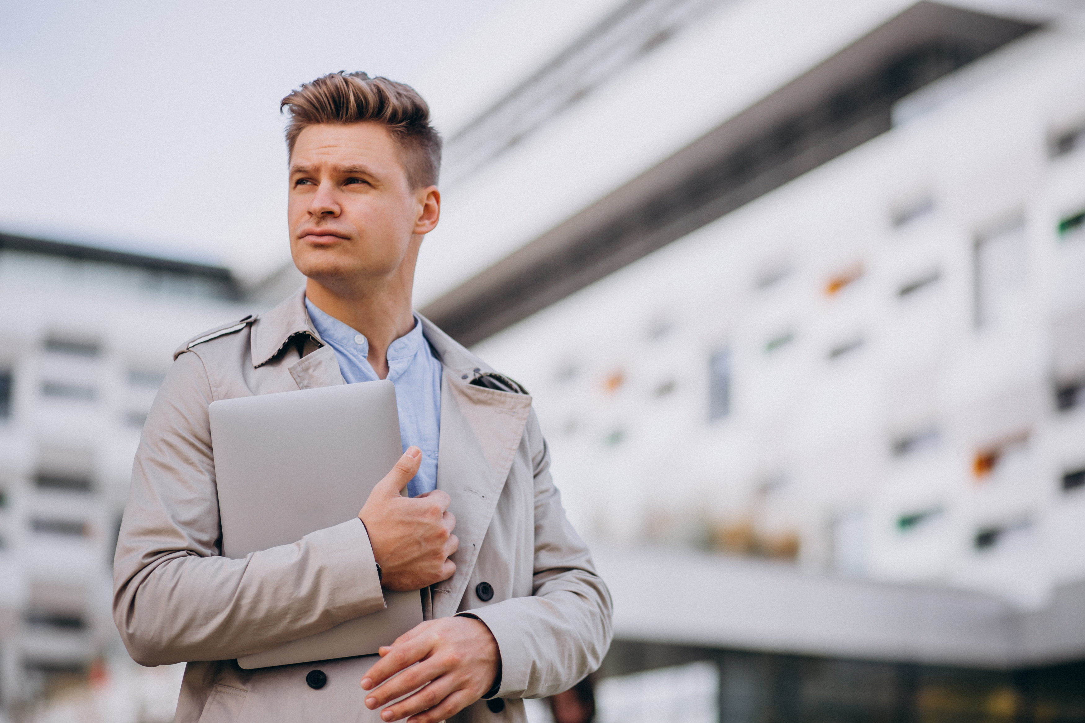 Young business man standing with laptop outside the business centre