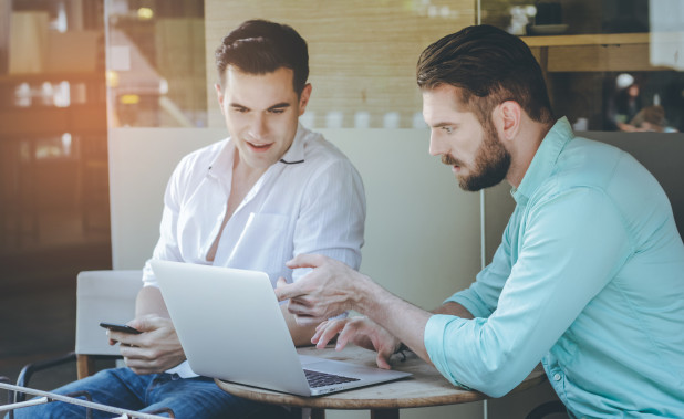 Two businessman meeting and brainstorming while using laptop at