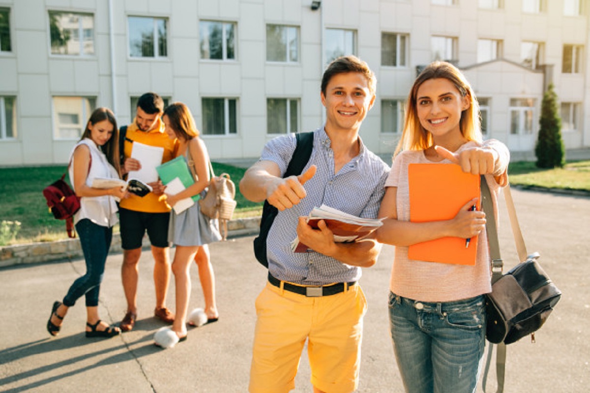 happy-two-young-students-with-note-books-backpacks-smiling-showing-thumb-up_8353-6386