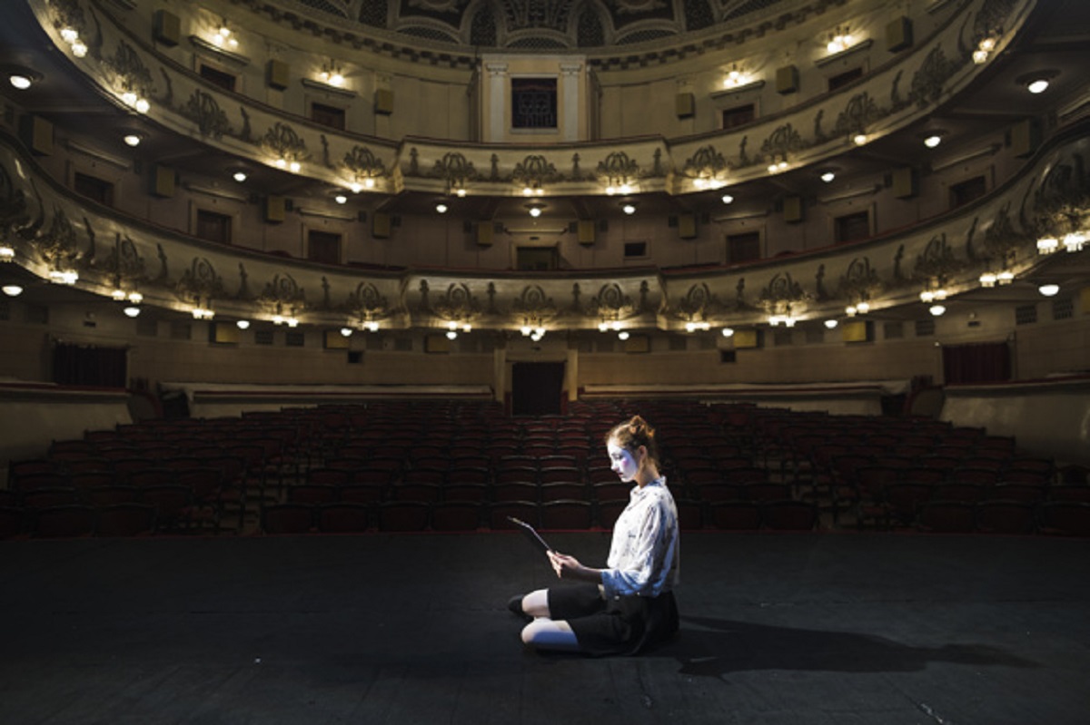 side-view-female-mime-reading-manuscript-empty-auditorium_23-2147891801